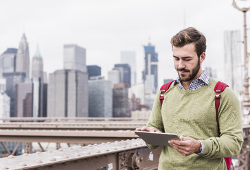 USA, New York City, Mann auf der Brooklyn Bridge mit Tablet - UUF09669