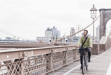 USA, New York City, Mann auf Fahrrad auf der Brooklyn Bridge - UUF09670