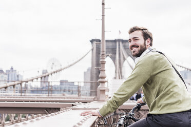 USA, New York City, lächelnder Mann auf Fahrrad auf der Brooklyn Bridge - UUF09671