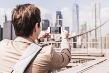 USA, New York City, Frau auf der Brooklyn Bridge beim Fotografieren mit dem Handy - UUF09678