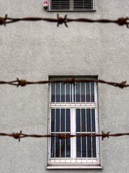 Barred window behind barbed wire - EJWF00819