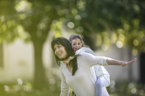 Mutter schaukelt ihre Tochter im Garten - ZEF12335