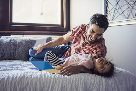 Vater und Tochter spielen auf dem Bett, lizenzfreies Stockfoto