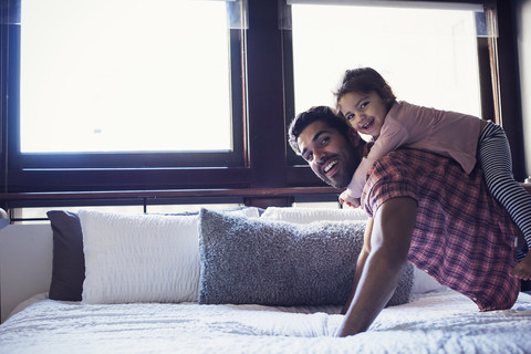 Vater und Tochter spielen auf dem Bett, lizenzfreies Stockfoto