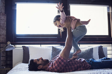 Father and daughter playing on bed - WESTF22461