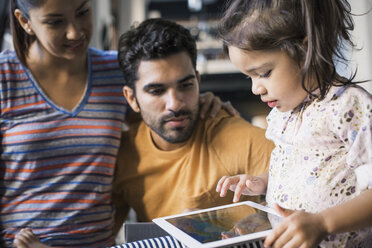 Mutter und Vater beobachten ihre Tochter bei der Nutzung eines digitalen Tablets - WESTF22470