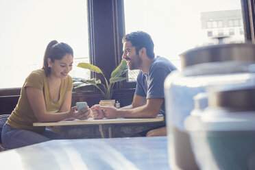 Young couple in kitchen using smart phone - WESTF22472