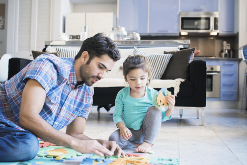 Vater und Tochter sitzen auf dem Boden und spielen mit einem Kinderpuzzle - WESTF22496