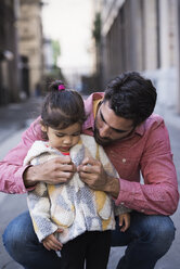 Father dressing daughter in warm coat - WESTF22501