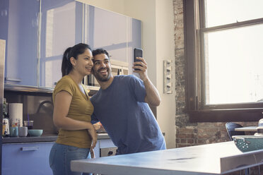 Young couple in kitchen taking selfie - WESTF22506