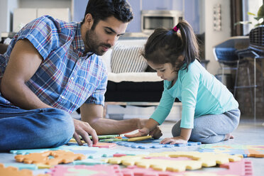 Vater und Tochter sitzen auf dem Boden und spielen mit einem Kinderpuzzle - WESTF22520