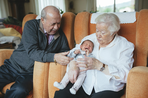 Urgroßeltern kümmern sich zu Hause um ihre Urenkelin, lizenzfreies Stockfoto