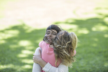 Mother hugging daughter in garden - ZEF12353