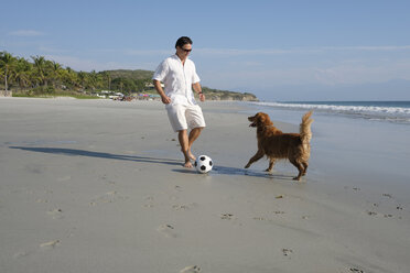 Man playing with his dog on the beach - ABAF02134