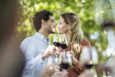 Couple kissing during lunch in garden with red wine - ZEF12364