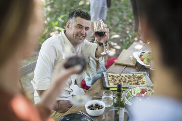 Friends and family having lunch in garden with red wine - ZEF12367