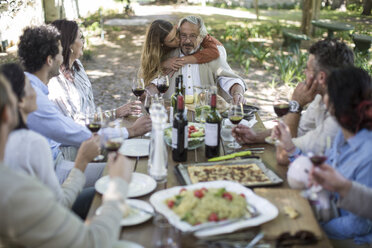 Adult daughter embracing father during lunch in garden - ZEF12370