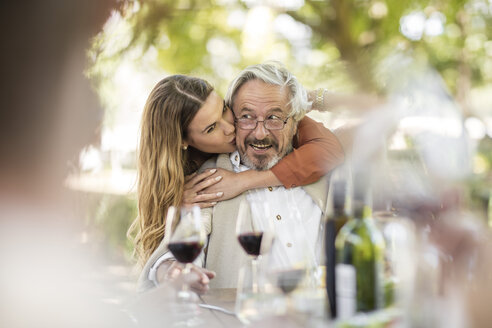 Erwachsene Tochter umarmt Vater beim Mittagessen im Garten - ZEF12371