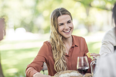 Smiling woman at family lunch in garden - ZEF12372