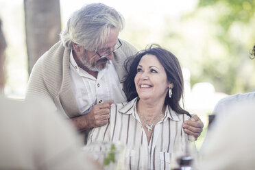 Senior man embracing his wife at outdoor table - ZEF12375