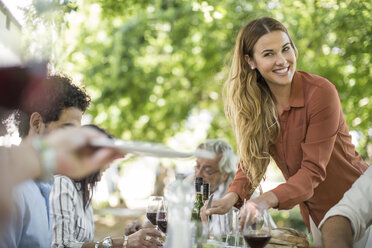 Smiling woman dishing up at family lunch in garden - ZEF12382