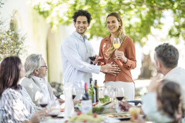 Young couple raising a toast with announcement of pregnancy to family during outside family lunch - ZEF12384