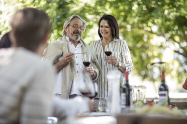 Senior couple raising a toast during family lunch in garden - ZEF12386