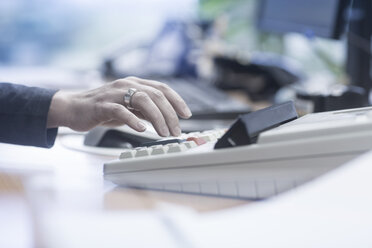 Close-up of woman using a calculator in office - SGF02072