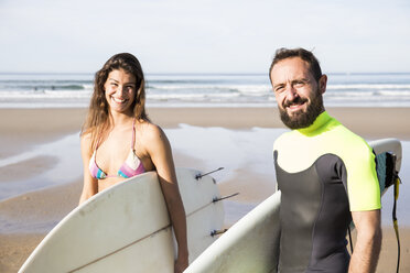 Glückliches Paar mit Surfbrettern am Strand - ABZF01715