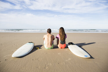 Pärchen mit Surfbrettern am Strand sitzend - ABZF01725