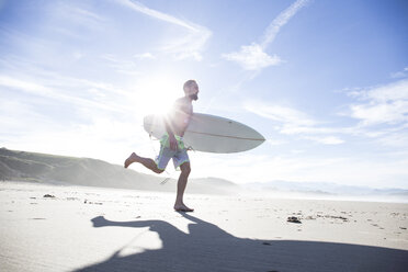 Mann mit Surfbrett läuft am Strand - ABZF01729