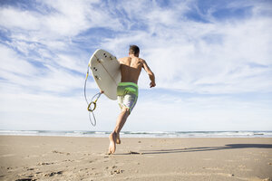 Mann mit Surfbrett läuft am Strand - ABZF01731