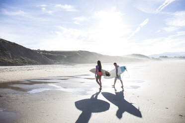 Couple carrying surfboards walking on the beach - ABZF01739