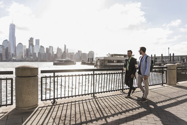 USA, zwei Geschäftsleute spazieren am Ufer von New Jersey mit Blick auf Manhattan - UUF09694