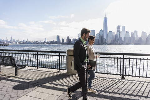 USA, Mann und Frau spazieren am Ufer von New Jersey mit Blick auf Manhattan, lizenzfreies Stockfoto