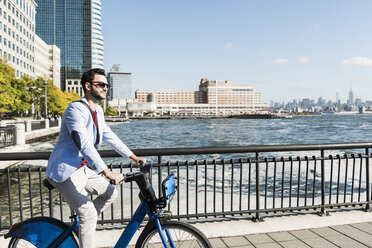 USA, Mann auf Fahrrad am Hafen von New Jersey mit Blick auf Manhattan - UUF09715