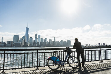 USA, man with bicycle at New Jersey waterfront with view to Manhattan - UUF09722