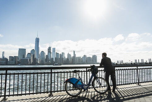 USA, Mann mit Fahrrad am Ufer von New Jersey mit Blick auf Manhattan - UUF09722