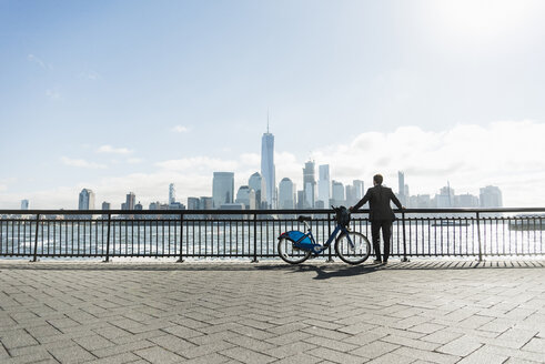 USA, Mann mit Fahrrad am Ufer von New Jersey mit Blick auf Manhattan - UUF09723