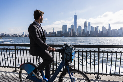USA, Mann auf Fahrrad am Hafen von New Jersey mit Blick auf Manhattan - UUF09724