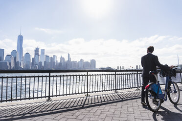 USA, man with bicycle at New Jersey waterfront with view to Manhattan - UUF09725