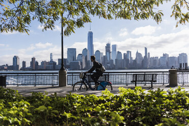 USA, man on bicycle at New Jersey waterfront with view to Manhattan - UUF09726