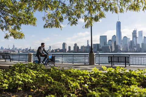 USA, Mann auf Fahrrad am Hafen von New Jersey mit Blick auf Manhattan, lizenzfreies Stockfoto