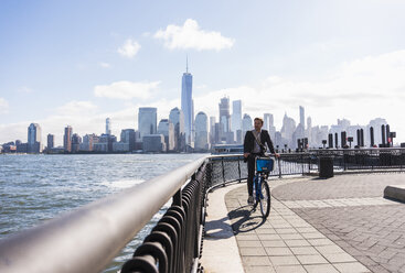 USA, man on bicycle at New Jersey waterfront with view to Manhattan - UUF09728