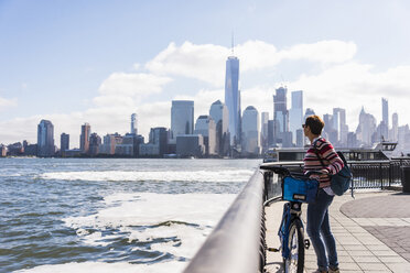 USA, Frau mit Fahrrad am Ufer von New Jersey mit Blick auf Manhattan - UUF09730