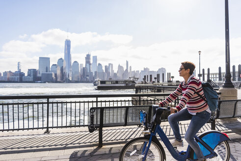 USA, Frau auf Fahrrad am Ufer von New Jersey mit Blick auf Manhattan - UUF09731