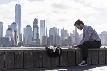 USA, Mann benutzt Tablet am Hafen von New Jersey mit Blick auf Manhattan - UUF09737