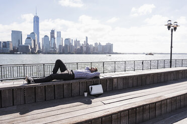 USA, man resting at New Jersey waterfront with view to Manhattan - UUF09740