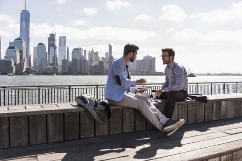 USA, zwei Geschäftsleute arbeiten am Hafen von New Jersey mit Blick auf Manhattan - UUF09743