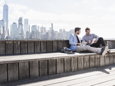 USA, zwei Geschäftsleute arbeiten am Hafen von New Jersey mit Blick auf Manhattan - UUF09745